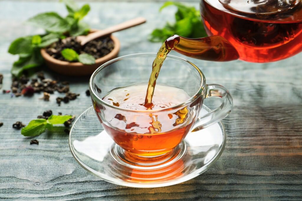 Pouring detox diet tea into glass cup